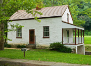 Lockhouse 6 is a white house with a porch on the side and green grass in front