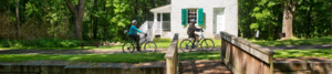 2 people ride bikes past Lockhouse 28